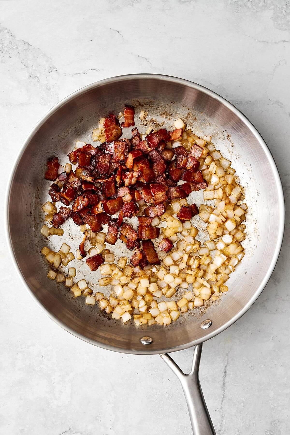 Cooking bacon and onion in a pan.