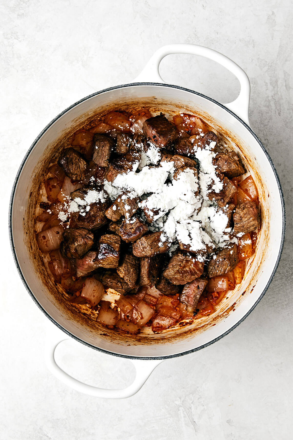Beef stew meat and arrowroot powder in a pot