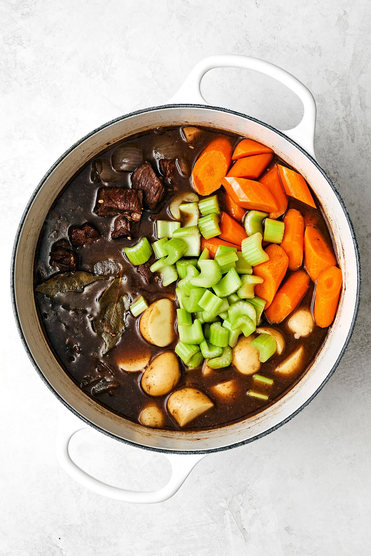 Adding veggies into a pot of beef stew