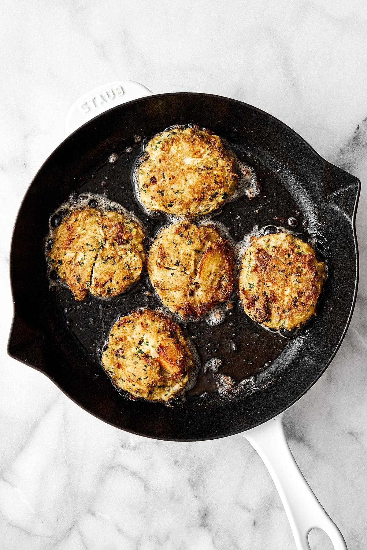 Fried crab cakes in a pan.