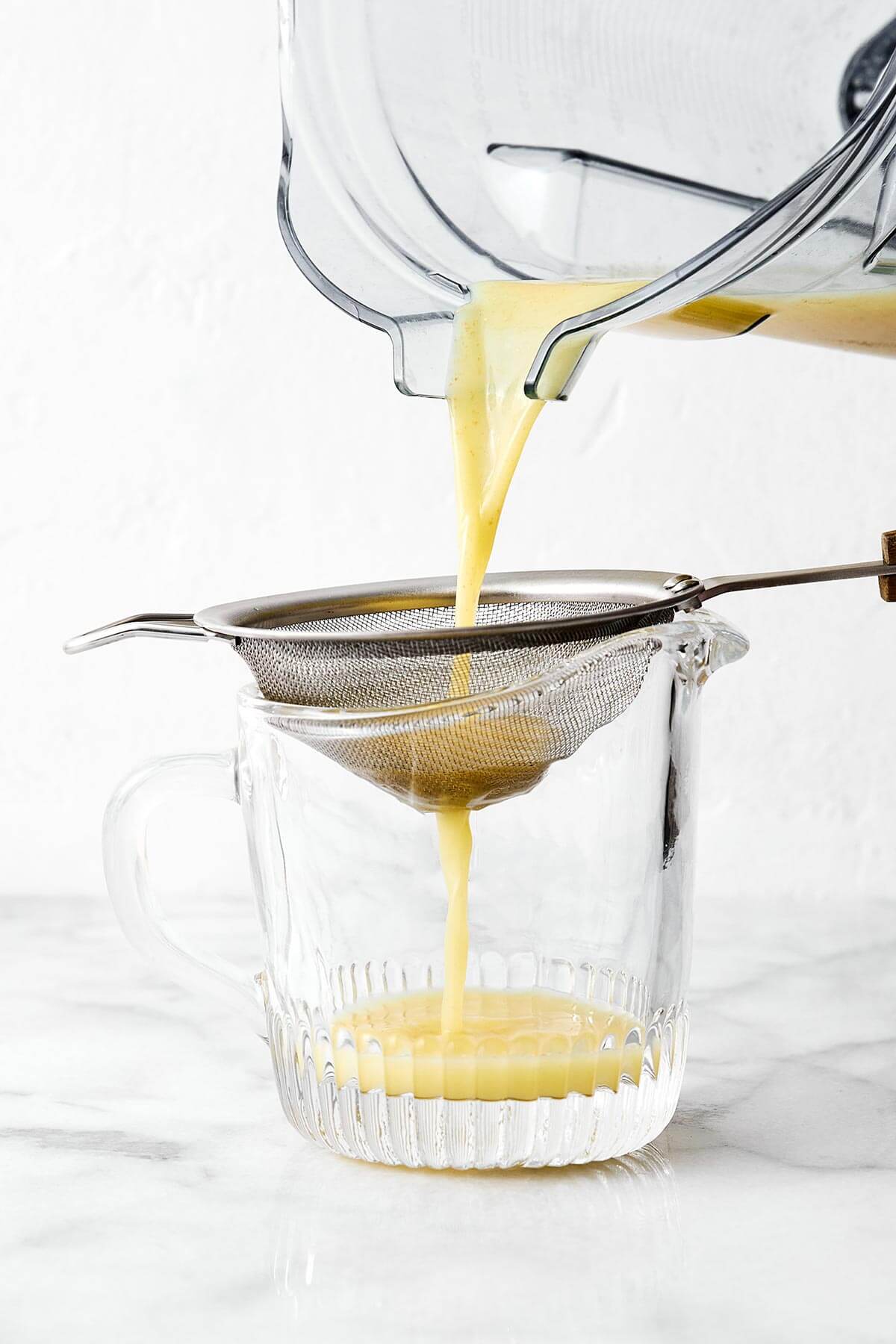 Straining ginger shots into a cup.