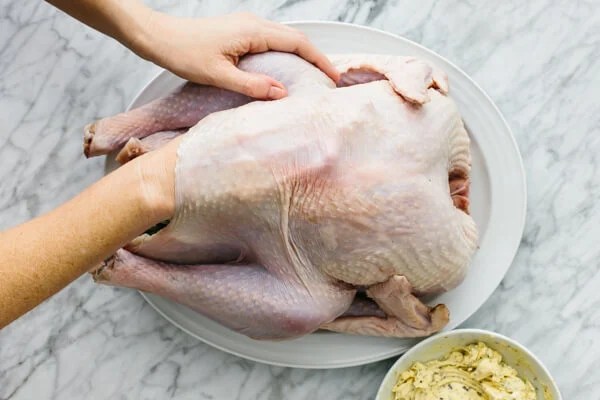 Rubbing herbed butter under the skin of a Thanksgiving turkey.