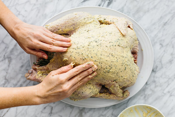 Rubbing herbed butter all over the skin of a Thanksgiving turkey