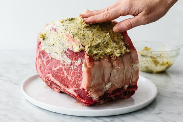 Coating the prime rib with garlic herb butter.