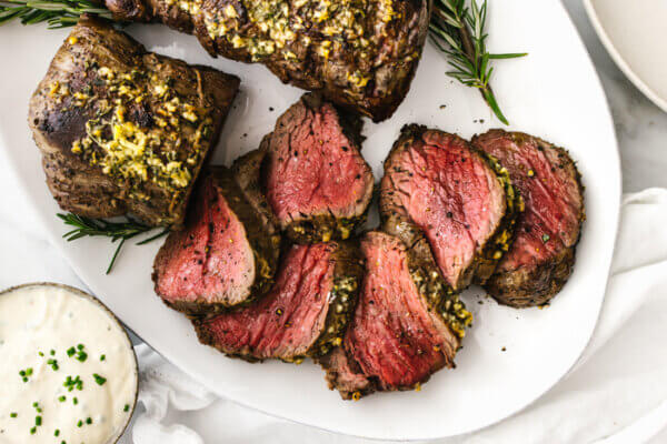 A plate of sliced beef tenderloin with horseradish sauce