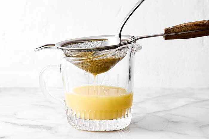 Straining ginger shots with a sieve.