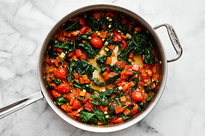 A pan with cooked tomatoes and spinach.