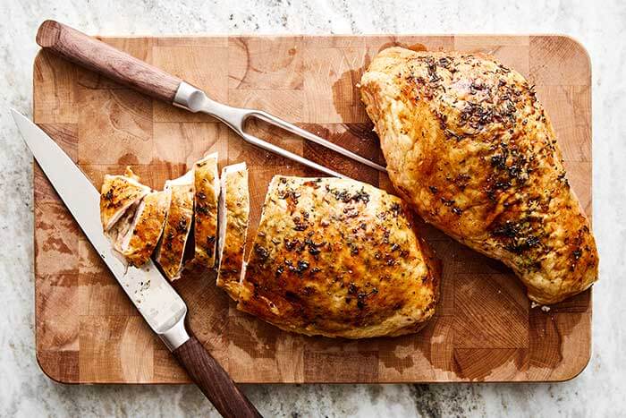 Wooden board with sliced turkey breast.