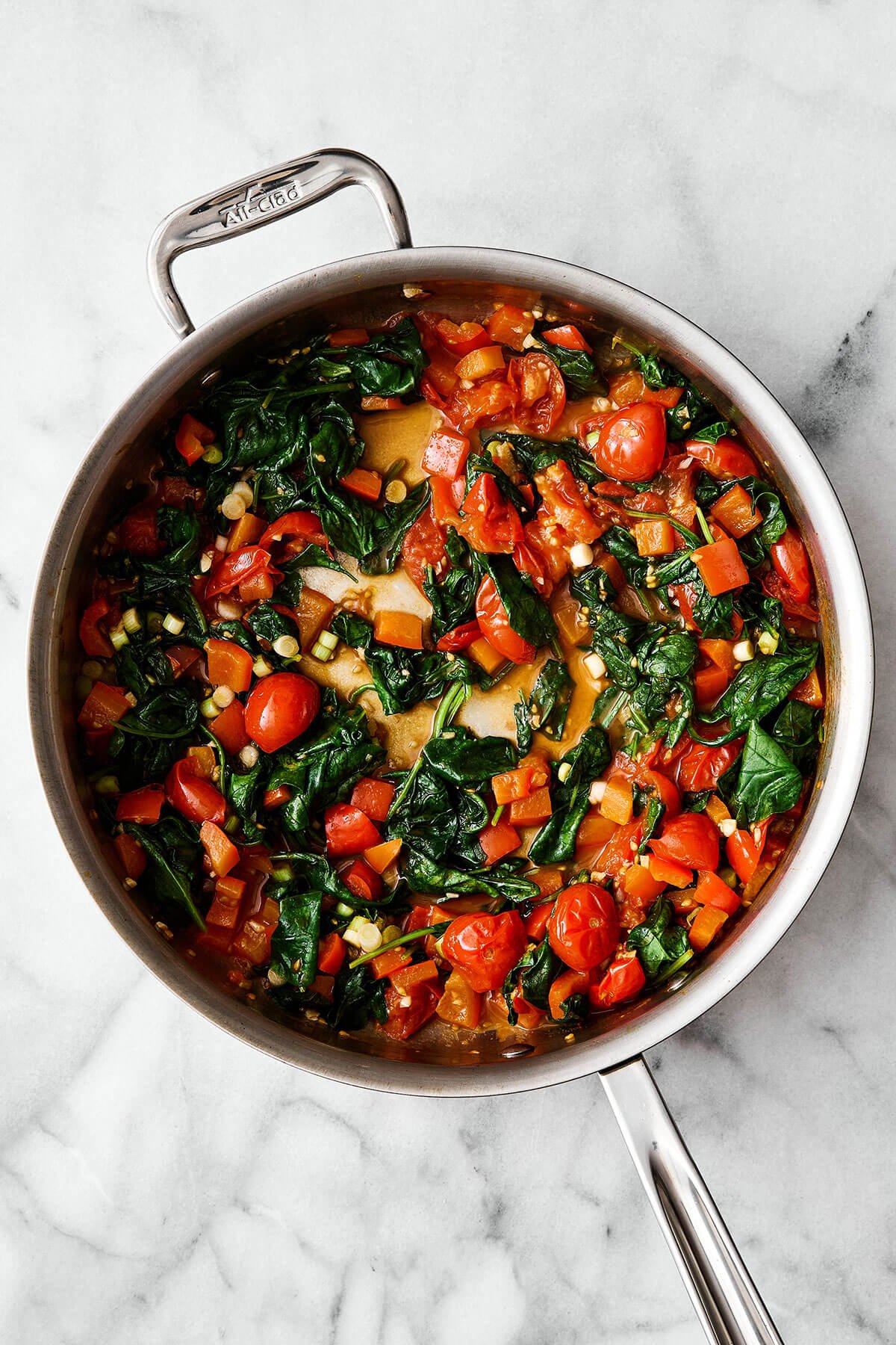 Cooked tomatoes and spinach in a pan.