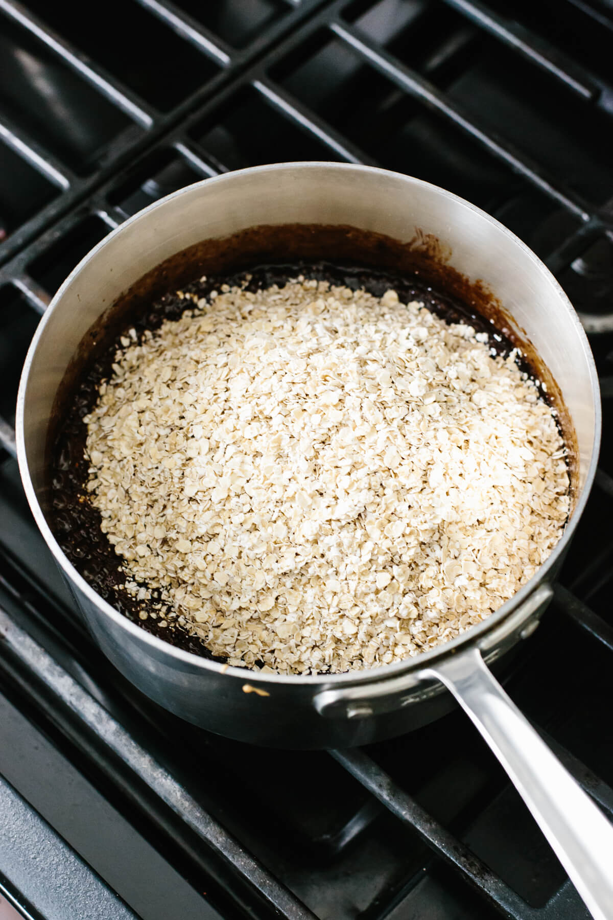 Adding oats to a chocolate mixture in a pot.