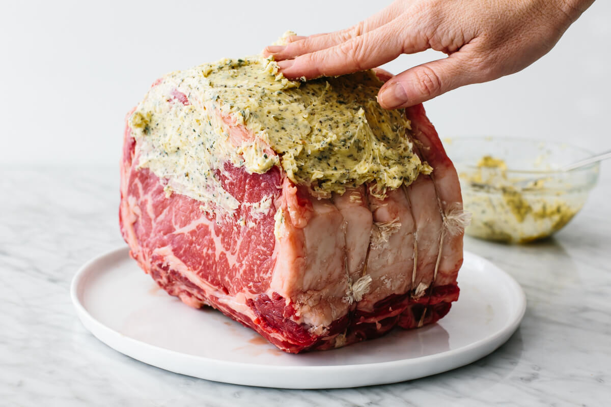 Adding garlic herb butter to prime rib.